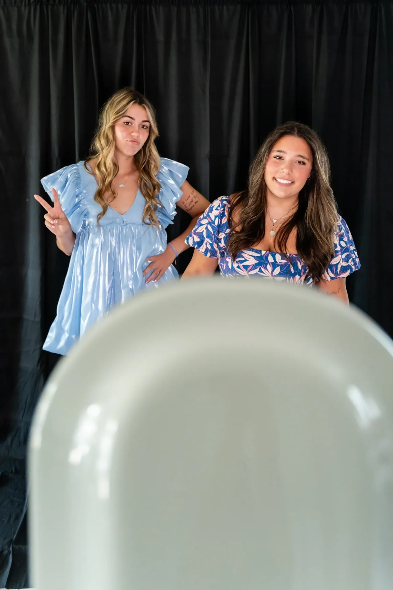 Two girls are posing for a picture in front of a mirror.